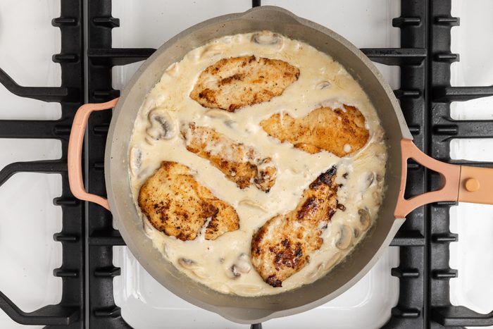 Cooked chicken being mixed with the sauce.