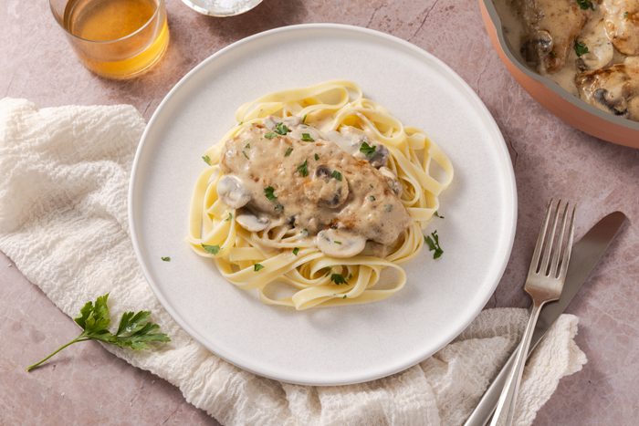 Creamy lemon chicken served on plate with pasta.