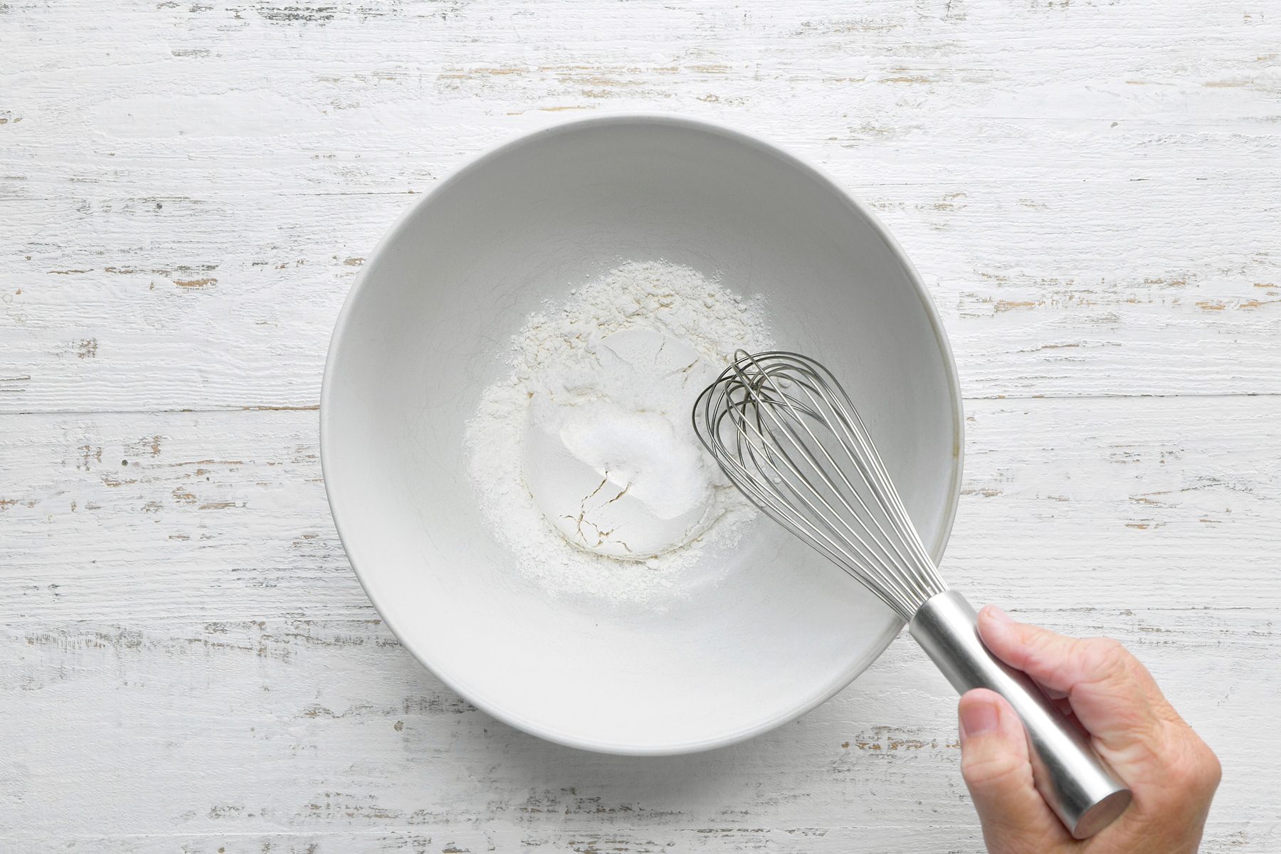 overhead shot of bowl placed white wooden background, mixing flour, sugar and salt