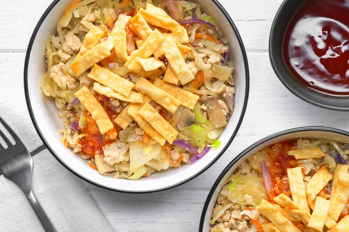 Two bowls of Egg Roll in a Bowl are showcased, The dish is topped with crispy fried wontons, A small bowl of sweet and sour sauce is placed on the side