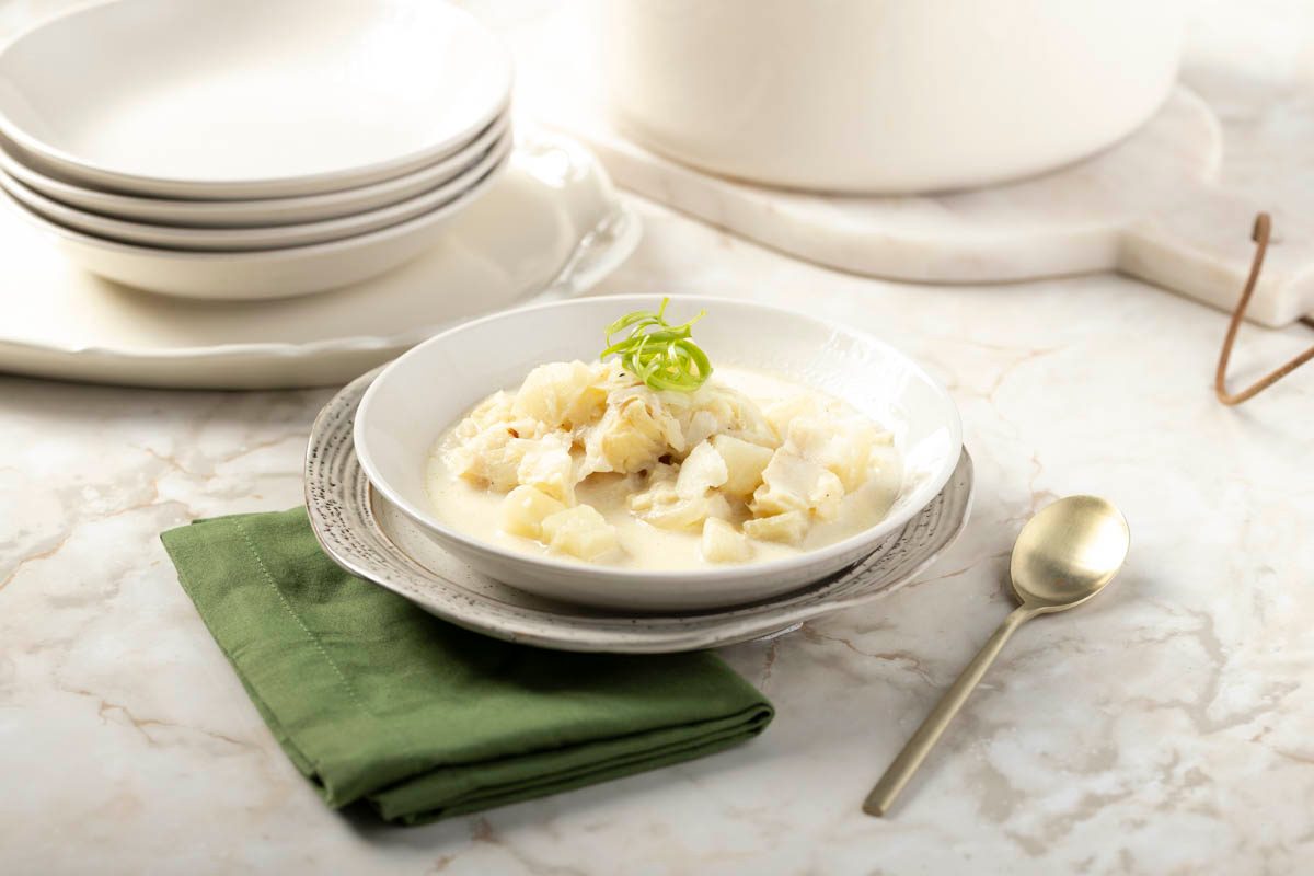 Fish Chowder in a white bowl at 3/4 view on marble table