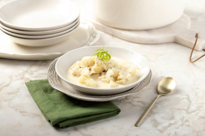 Fish Chowder in a white bowl at 3/4 view on marble table