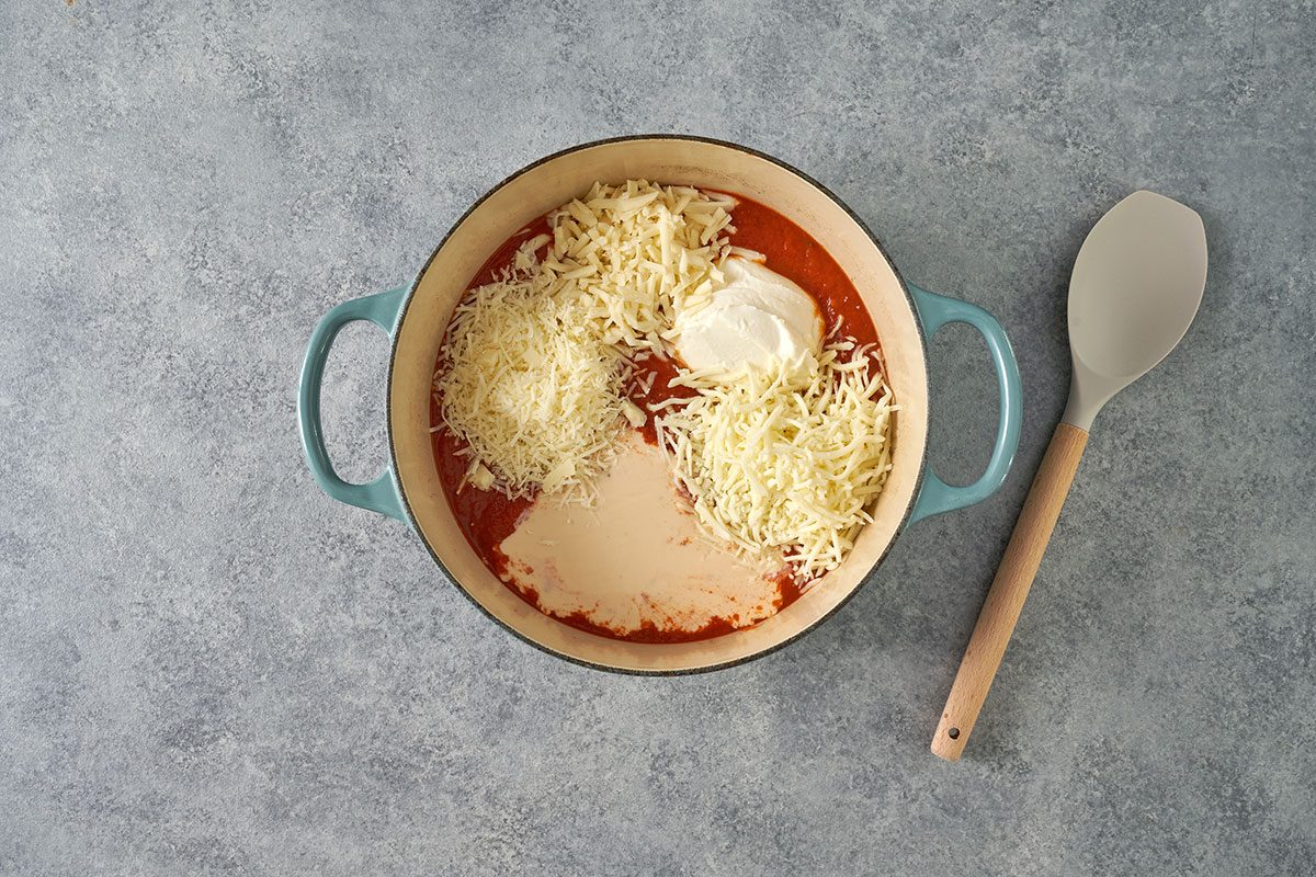 In a large Dutch oven, prepare the cheese sauce by combining marinara, Alfredo, mozzarella, ricotta, provolone, and Romano. Stir until melted for the Five-Cheese Ziti recipe by Taste of Home.