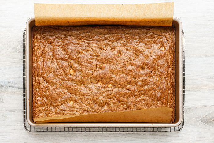 Baked gingerbread blondies with white chocolate chips, cooling on a rack.