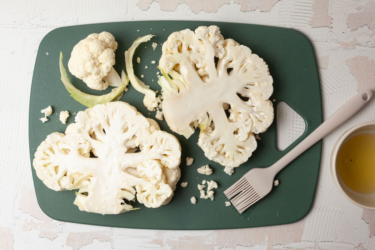 Step 1 of Taste of Home Grilled Cauliflower Steaks is to cut through the core of the cauliflower into four 1 inch thick steaks. Brush both sides of the cauliflower with oil.