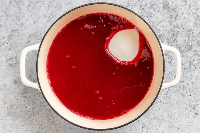 adding the sugar, lemon and orange juice to the cranberry juice.