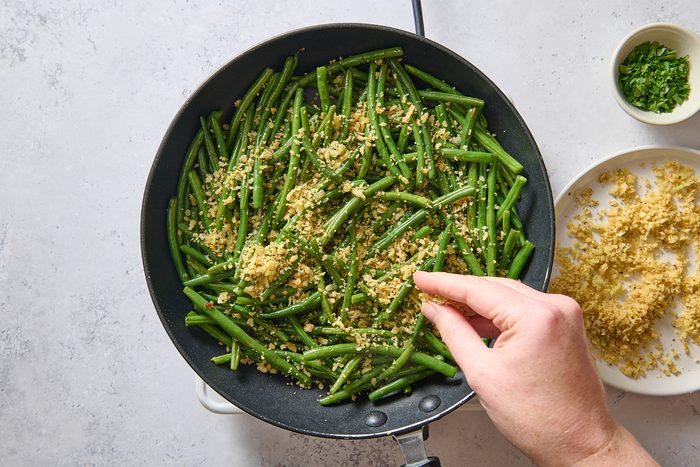 Sprinkling seasoned breadcrumbs over the sautéed green beans