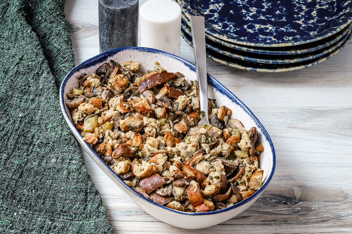 A serving bowl with keto stuffing, made with low carb keto bread, mushrooms, onion, celery, sage, and parsley.