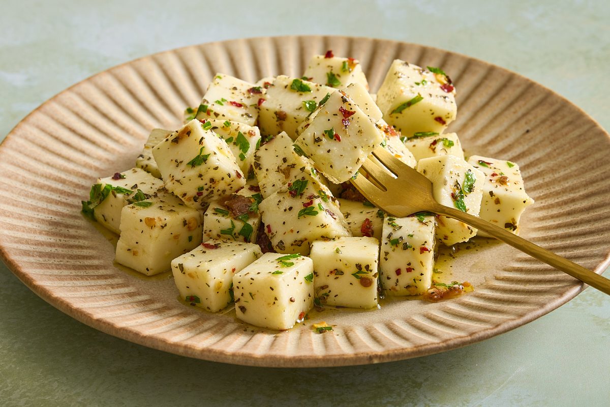 Cloesup of a plate full of marinated mozzarella with one piece skewered onto a fork
