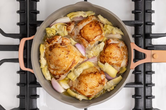 Shallots, artichoke hearts and white wine added to the skillet with cooked chicken.