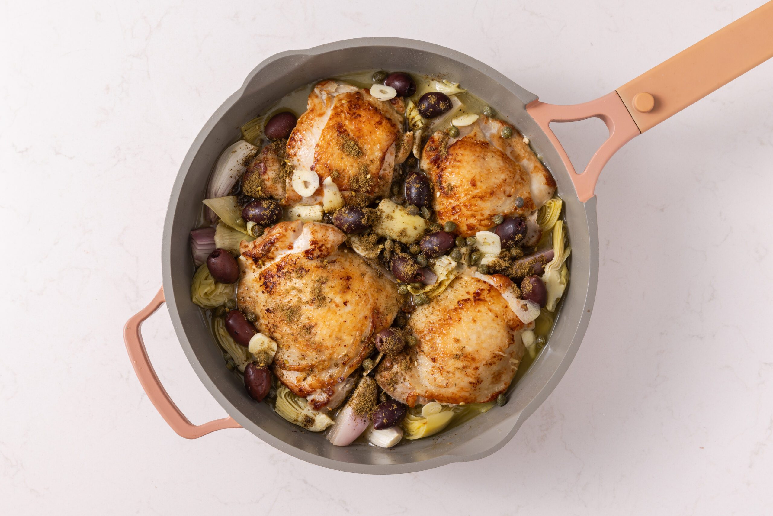 Olives, lemon juice, chicken broth, capers, garlic and zaatar added to the skillet before going into the oven.
