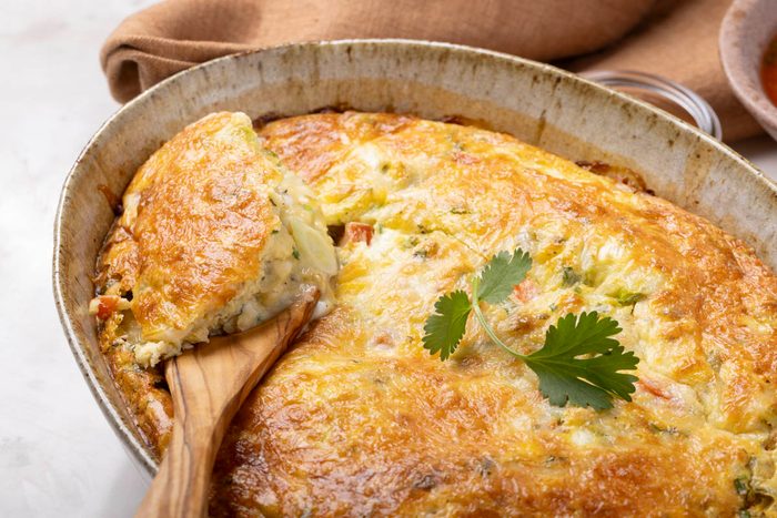 Mexican Breakfast Casserole in a baking dish with wooden spoon on marble table