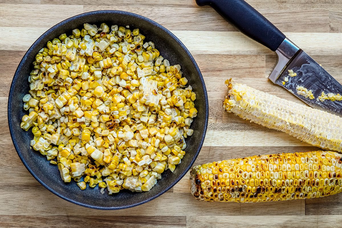 Grilled charred corn cut from the cobs, in preparation for Mexican street corn pasta salad.