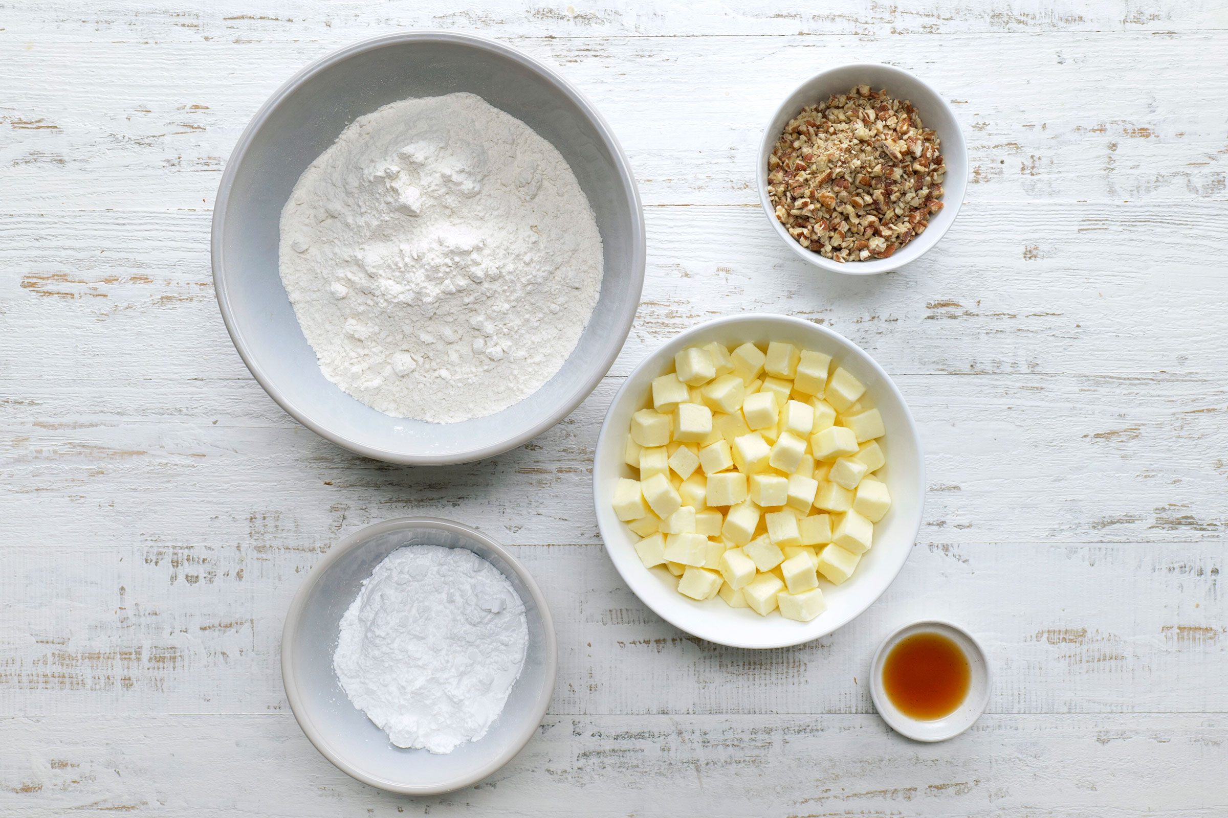 Butter, sugar, confectioners sugar, flour, vanilla extract and pecans in small bowls