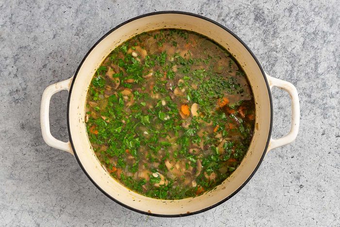 Taste of Home Mushroom Barley Soup recipe photo of simmered soup with barley and parsley.