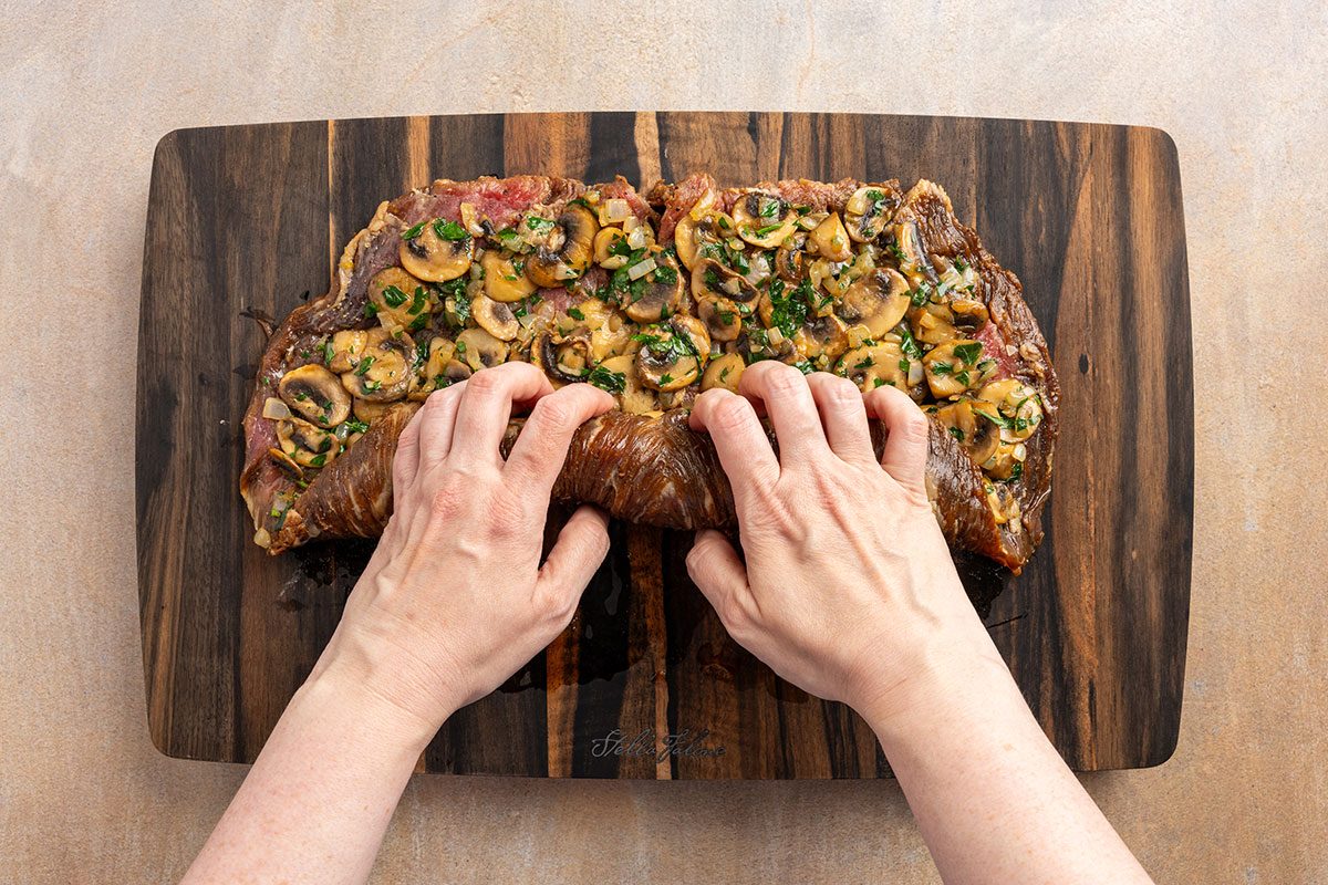 butterflied flank steak being rolled with sauteed mushrooms and onion.