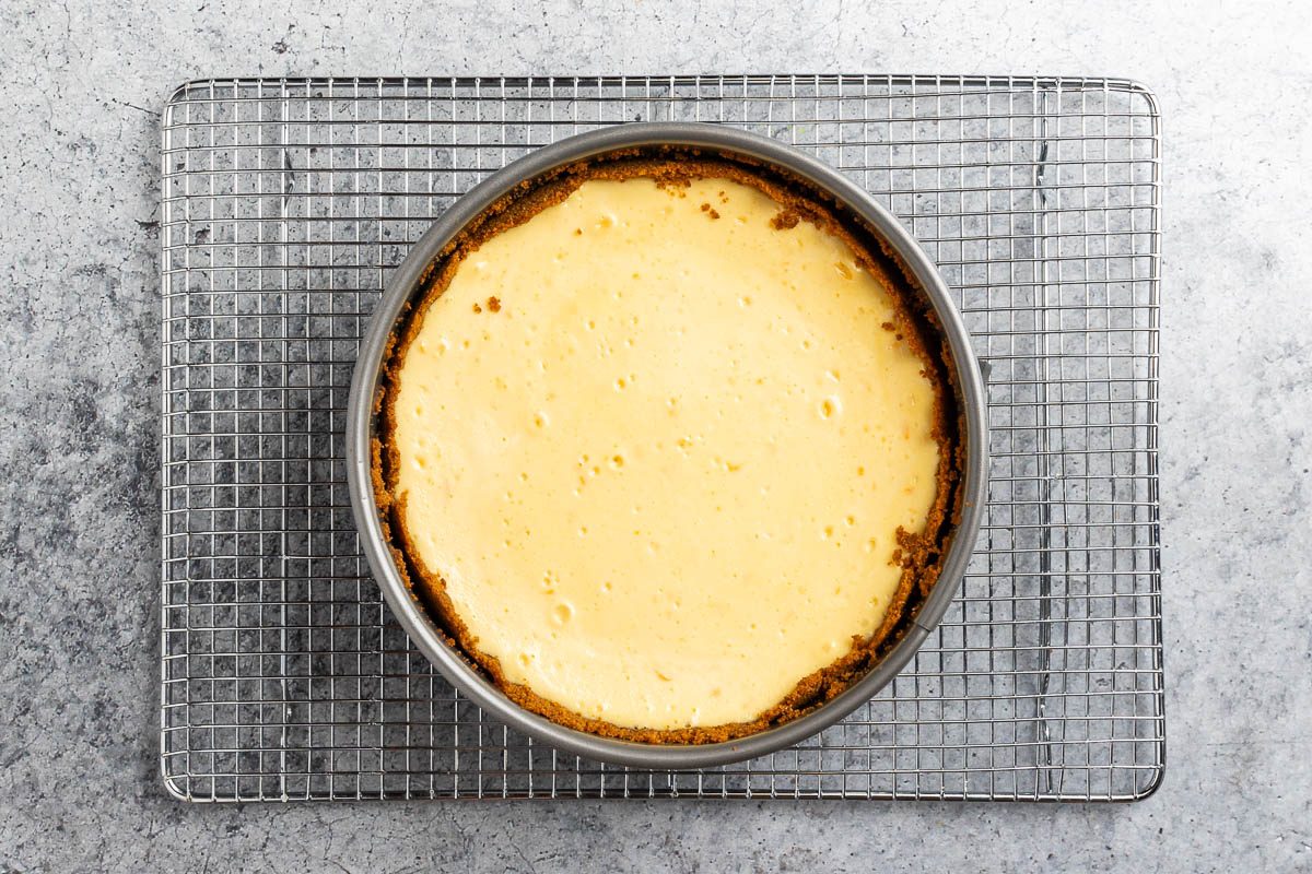 baked cheesecake cooling on a wire rack.