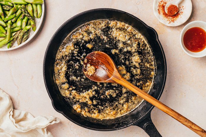 Garlic and red pepper flakes being cooked in butter and oil for the Pasta with Asparagus recipe by Taste of Home