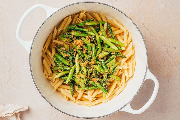 Asparagus mix added to a large pot with cooked pasta for Pasta with Asparagus recipe by Taste of Home