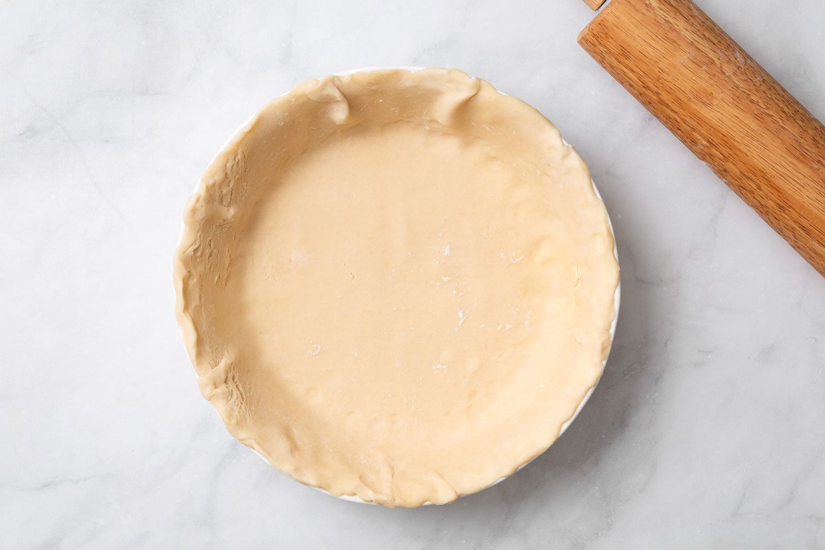 Rolled dough placed in a 9 inch pie plate for step two of Peach and Blueberry Pie recipe for Taste of Home