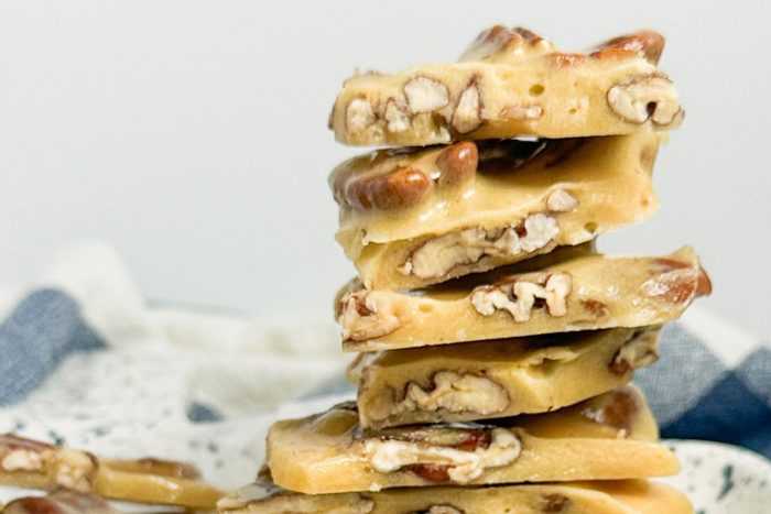 Taste of Home Pecan Brittle stacked on a speckled ceramic tray