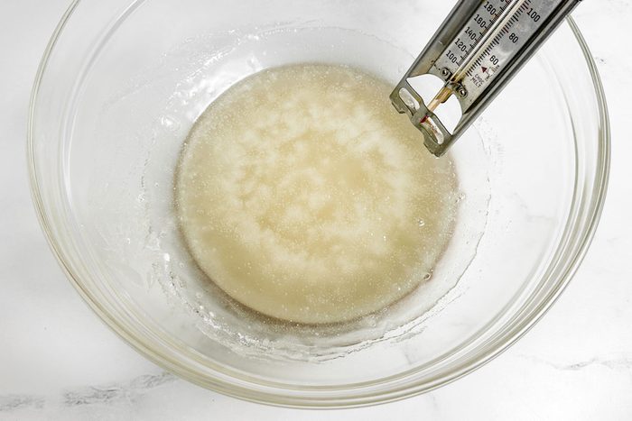 Sugar syrup for Taste of Home Pecan Brittle in a glass bowl with candy thermometer