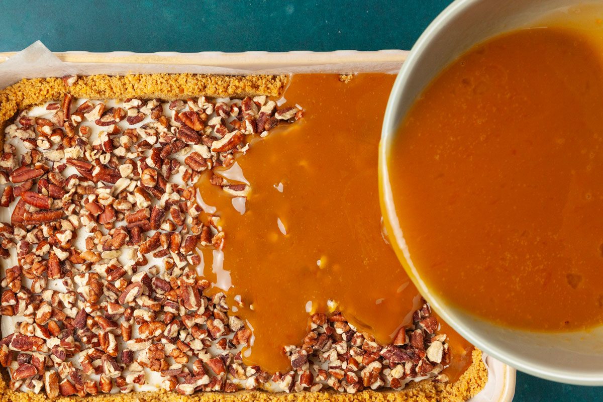 Step 3 of Taste of Home Pecan Pie Cheesecake Bars is to whisk the eggs and caramel sauce until blended and slowly pour it over the pecans.