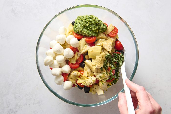 Combining the tortellini salad ingredients in a large bowl