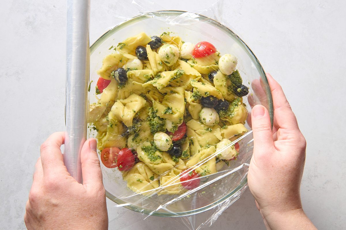 Covering the bowl of pesto tortellini salad ready for chilling