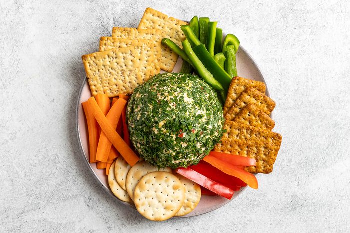 Taste of Home Pimento Cheese Ball photo of the formed cheese ball rolled in fresh parsley and served with assorted crackers and vegetables.