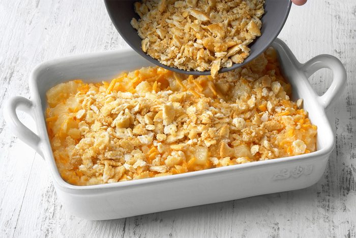 3/4th shot of Transferring batter to a greased baking dish over white wooden background