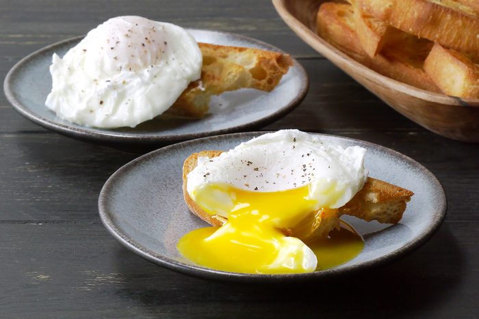 3/4 shot of poached eggs served alongside slices of toast.