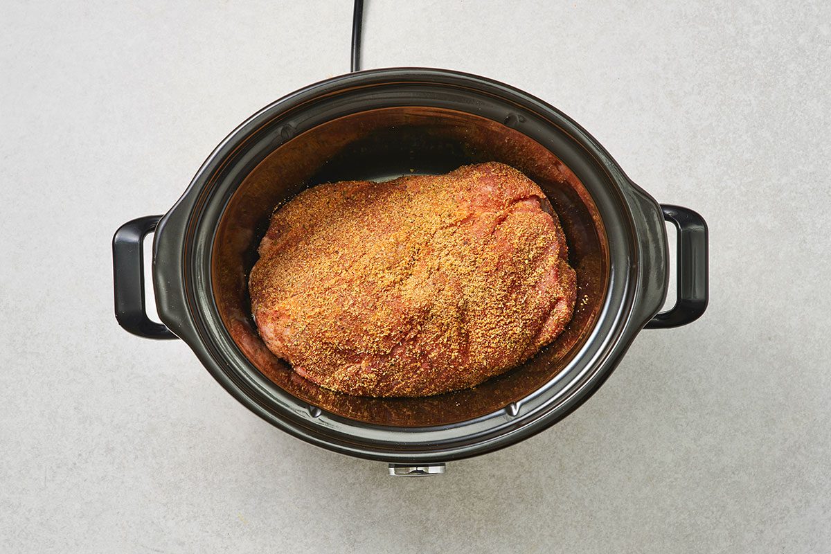 Pork butt roast rubbed with a spice mix in a slow cooker