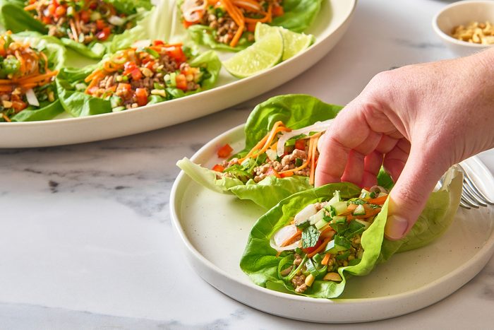 Closeup of a hand folding one of the pork lettuce wraps on a plate