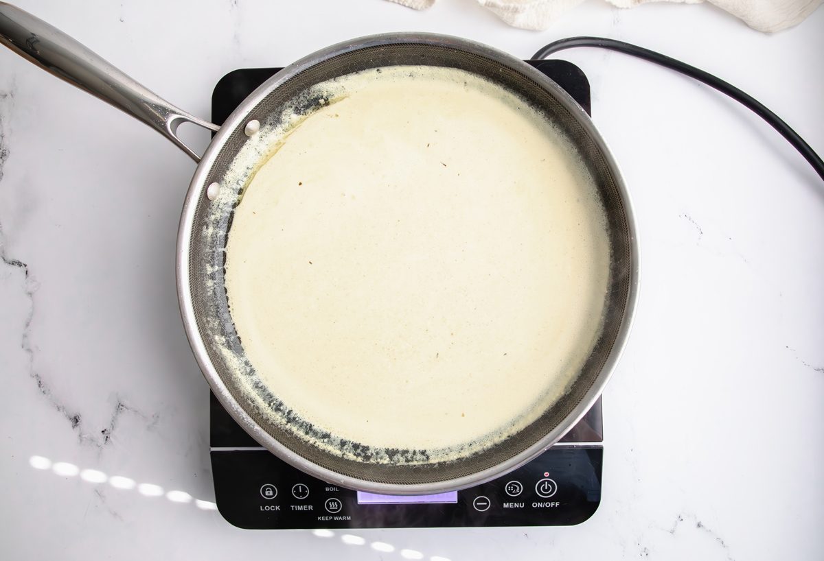 Overhead shot for Taste of Home Pork Chops and Noodles, creamy sauce cooking over an induction cooktop.
