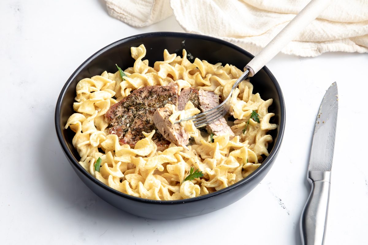 Close up beauty shot for Taste of Home Pork Chops and Noodles, being served in a black bowl.