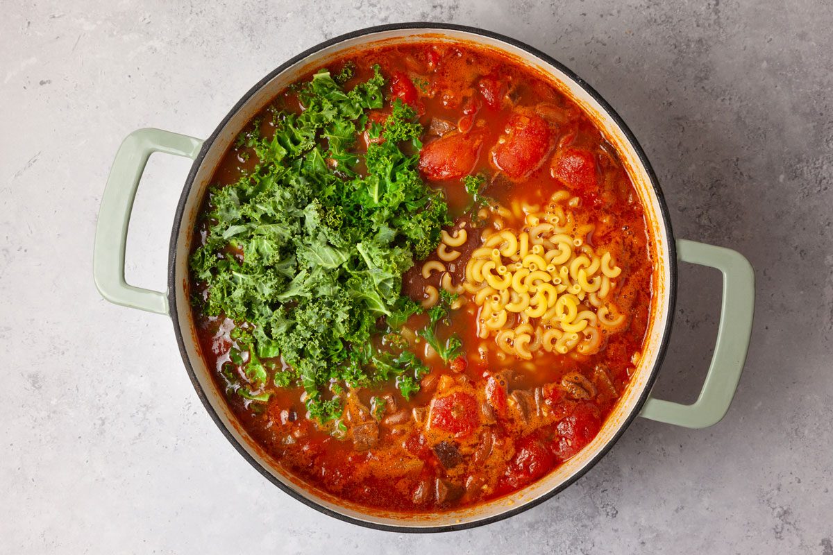 Step 3 of Taste of Home Portuguese Bean Soup is to add the kale and noodles
