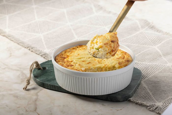 baked puffed and golden Potato Souffle in dish on marble at 3/4 view with spoon