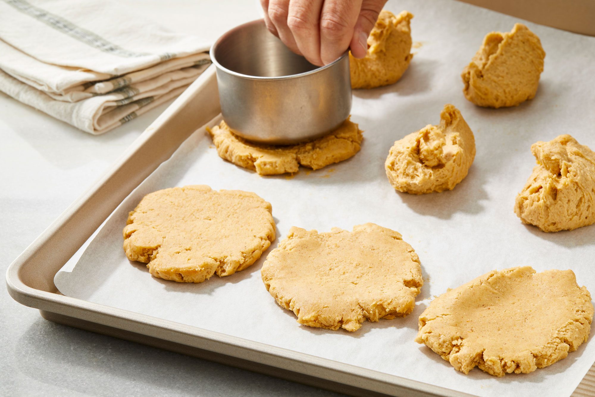 Same baking sheet of cookie dough balls now chilled being flattened