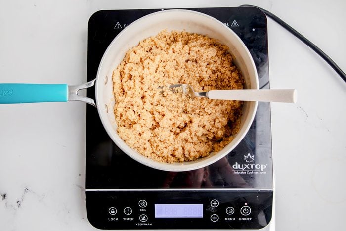 Overhead shot for Taste of Home Quinoa with Vegetables, quinoa being fluffed with a fork over an induction cooktop.