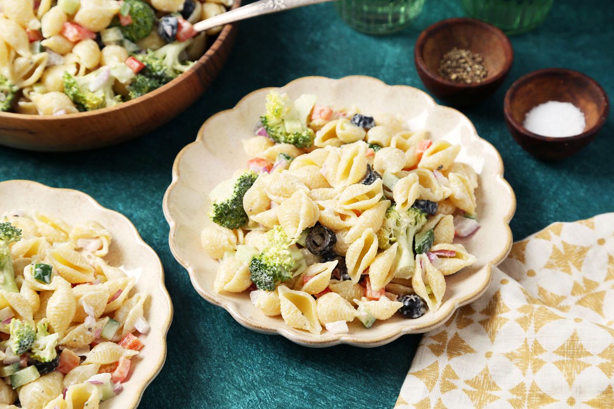Close up of Taste of Home's Creamy Pasta Salad served on plates on a green surface.