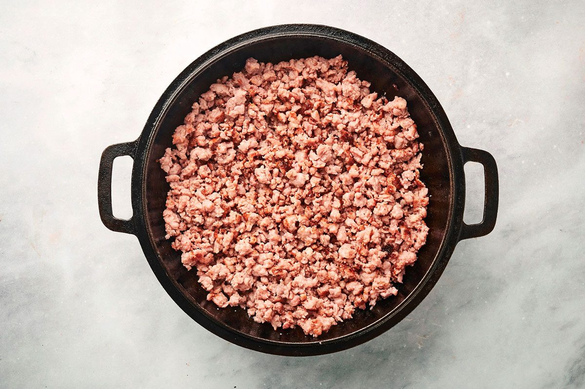 Browning the sausage in a large cast iron skillet for the Sausage Hash recipe by Taste of Home