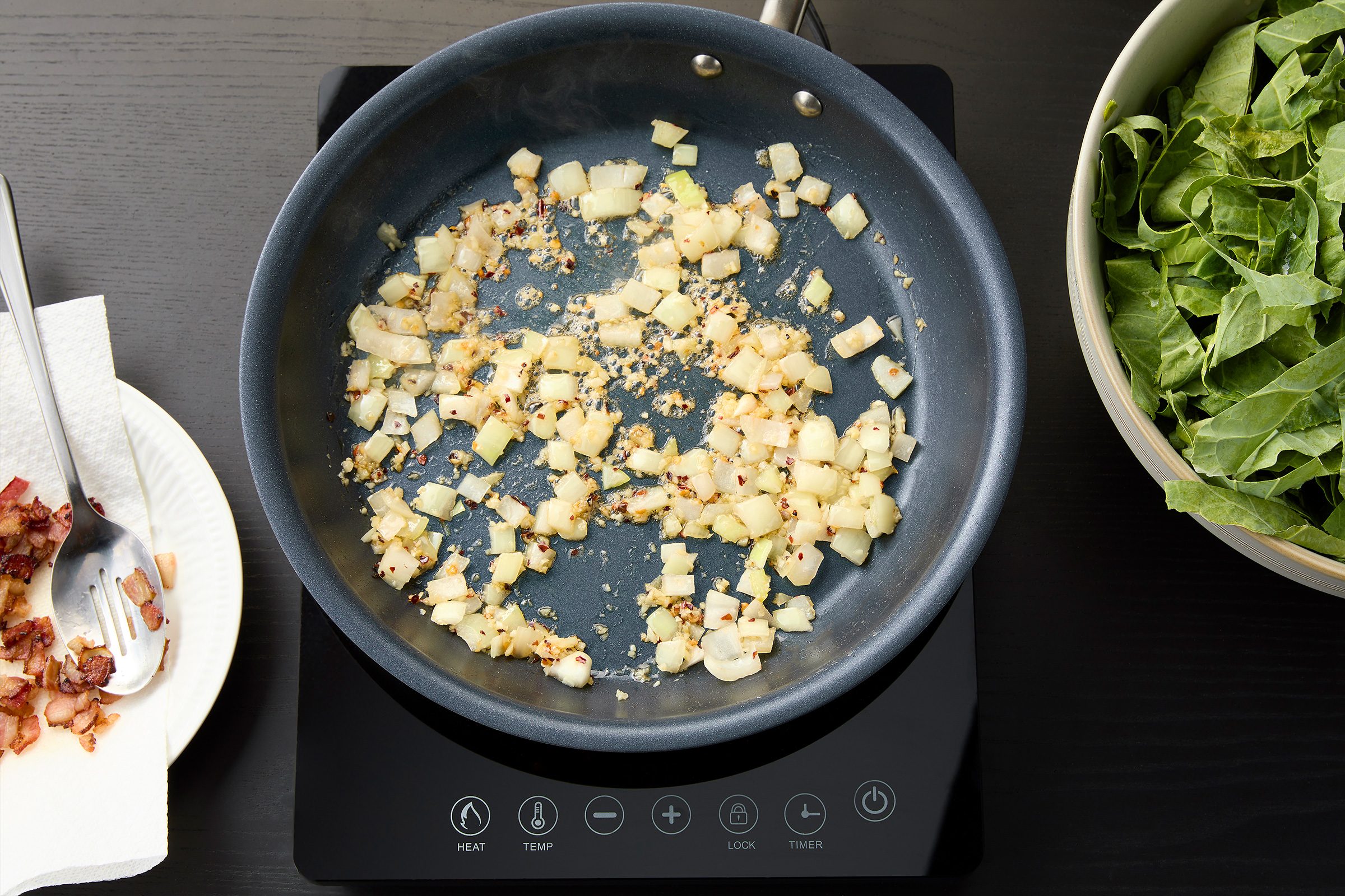 Cooking onion garlic and red chilli flakes and cooked bacon on the side on a paper towel
