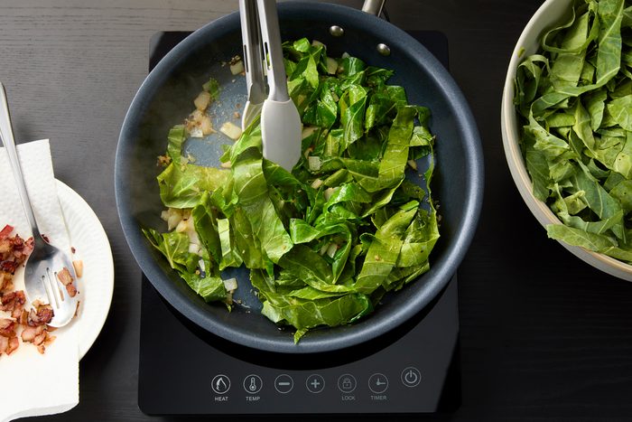 adding the prepared collard greens to the skillet after the first batch wilted
