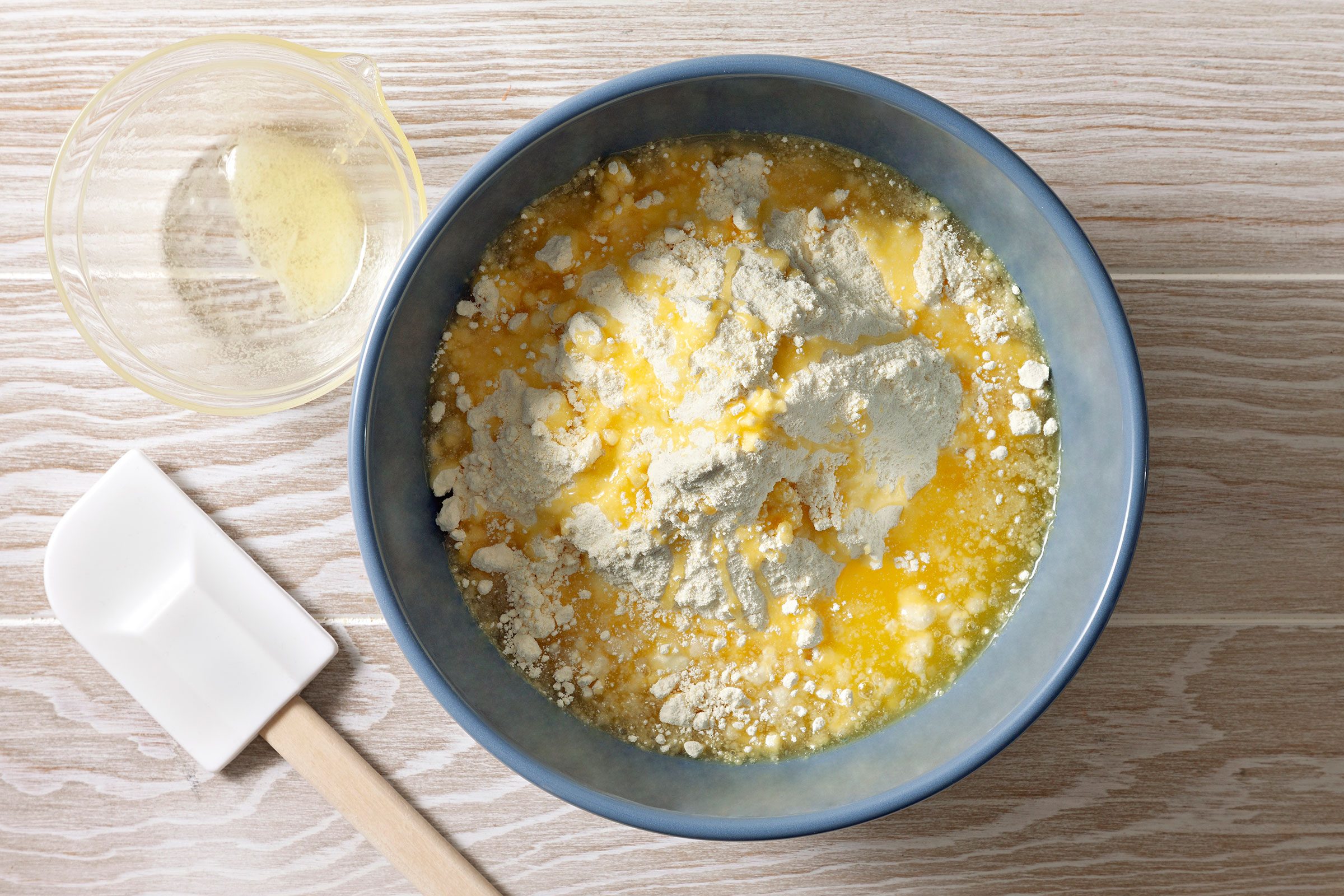 Cake mix with melted butter in a blue bowl with a spatula