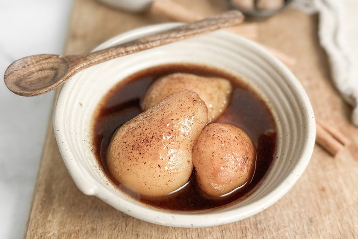 Taste of Home Spiced Pears in a ceramic bowl with wooden spoon on a wooden board