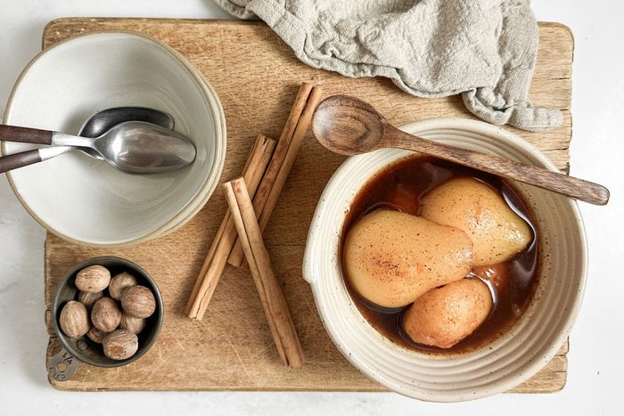 Taste of Home Spiced Pears in a ceramic bowl with wooden spoon on a wooden board