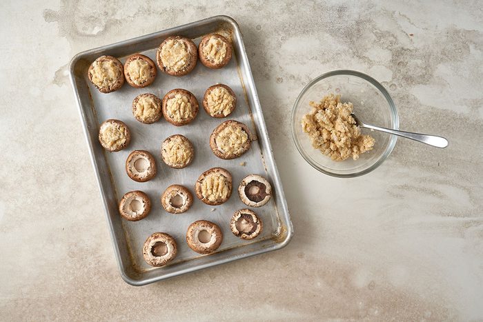 Combining crabmeat, mayonnaise, bread crumbs, Parmesan cheese, and garlic to stuff the mushroom caps for the Stuffed Mushrooms with Crabmeat recipe, by Taste of Home.
