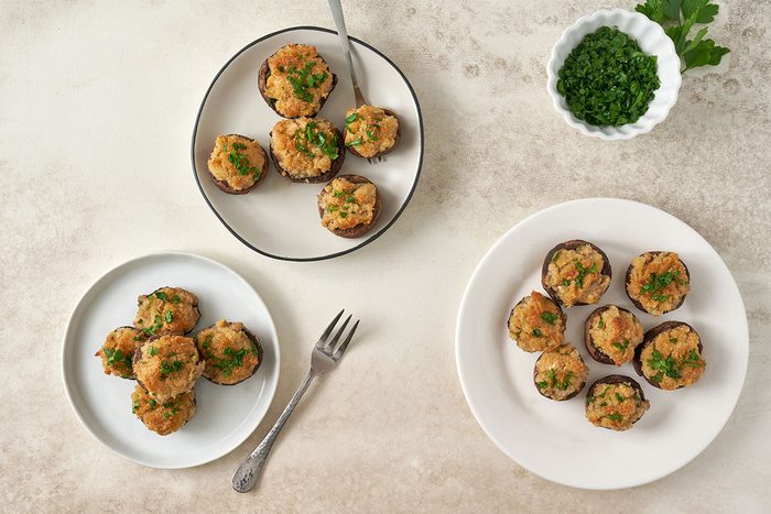 An overhead view of baked Stuffed Mushrooms with Crabmeat, golden and tender, arranged on a serving dish, by Taste of Home.