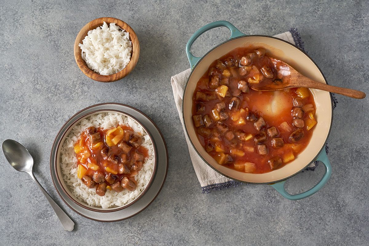 An overhead of the Sweet-and-Sour Sausage served over rice, with chunks of sausage and pineapple in a thick sweet-and-sour sauce, by Taste of Home.